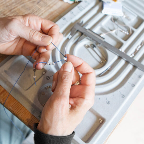 Perlen werden aufgefädelt und geknotet